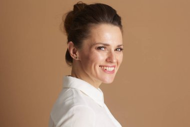 Beyaz yakalı, kendine güvenen profesyonel bir kadın arkasını kollarken içten bir şekilde gülümsüyor ve yaklaşımına ve uzmanlığına önem veriyor..