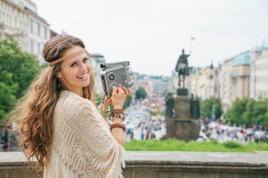 Happy hippy-looking woman tourist  with retro camera  in Prague