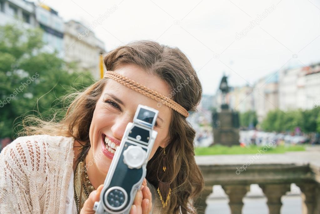 Joyful hippy-looking woman tourist using retro camera  in Prague