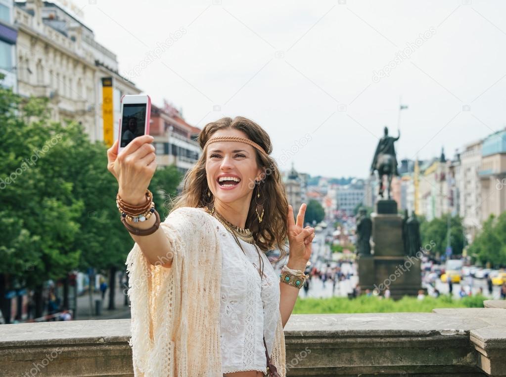 Hippie woman showing victory gesture and making selfie in Prague