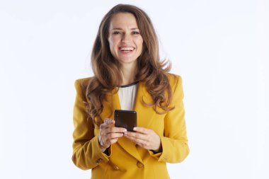 Bu orta boy fotoğraf, elinde akıllı bir telefonla gülümseyen sarı ceketli kendine güvenen bir iş kadınını gösteriyor. Modern iletişim, profesyonellik ve olumlu kadın yetkilendirmesi taşır..