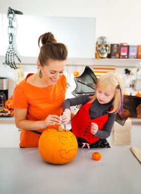 Happy mother with daughter creating Jack-O-Lantern on Halloween