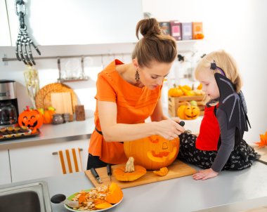 Mother with daughter carving Jack-O-Lantern for Halloween party