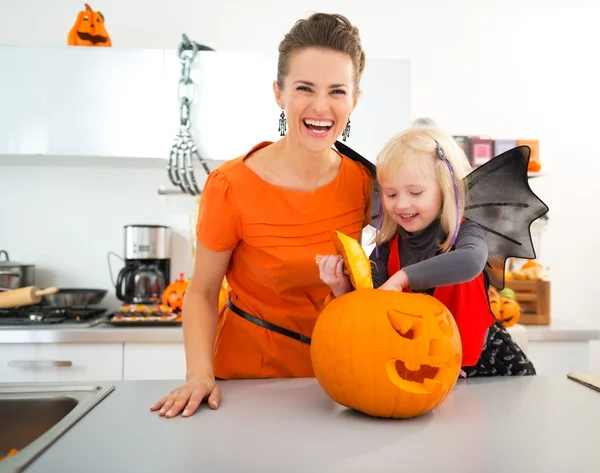 Chica vestida de Halloween con madre preparando Jack-O-Lantern —  Fotos de Stock