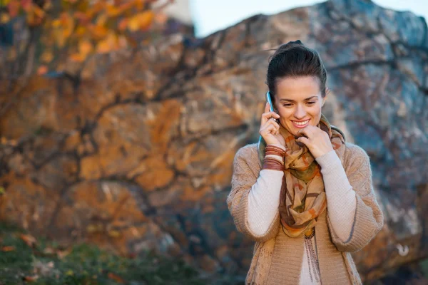Woman talking cell phone while walking in autumn outdoors — Stock Photo, Image