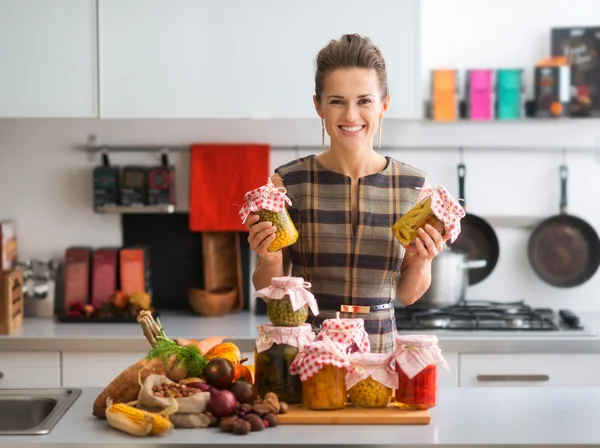 Mujer feliz en la cocina sosteniendo frascos de verduras conservadas — Foto de Stock