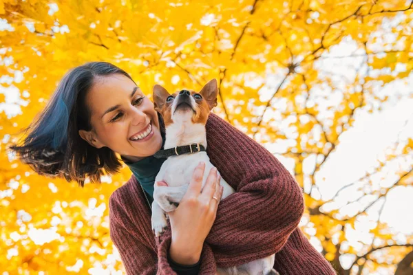 Retrato de mujer feliz joven con pequeño perro lindo en el parque —  Fotos de Stock