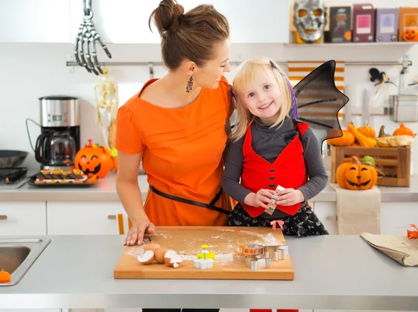 Halloween dressed girl with mother cutting out cookies — Stock fotografie