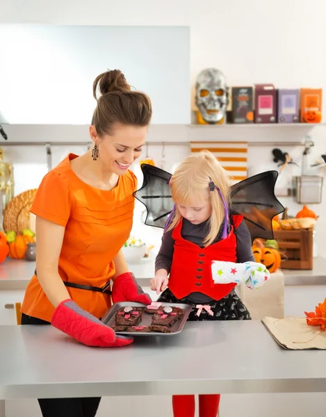 Halloween chica vestida con madre sosteniendo bandeja con galletas —  Fotos de Stock