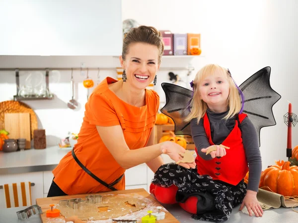 Smiling halloween dressed girl with young mother making biscuits — Zdjęcie stockowe