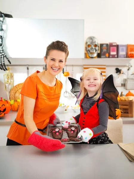 Chica con madre sosteniendo bandeja con galletas de Halloween en la cocina — Foto de Stock