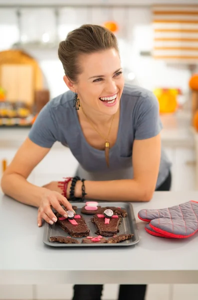 Lächelnde Hausfrau dekoriert frisch gemachte Halloween-Kekse — Stockfoto