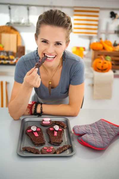 Dona de casa comer biscoitos de Halloween caseiros na cozinha — Fotografia de Stock