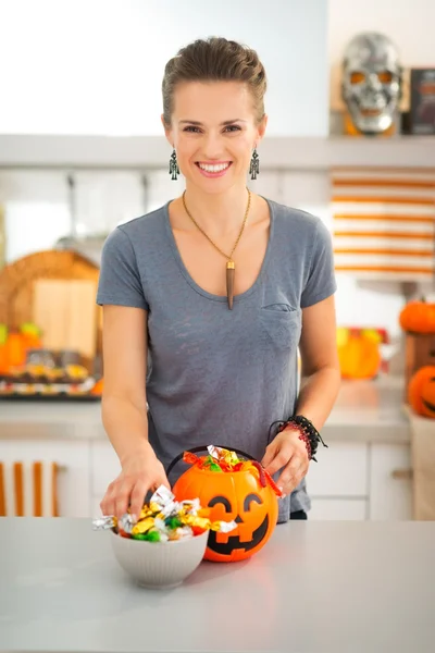 Smiling woman preparing halloween trick or treat candy for kids — Stock Photo, Image