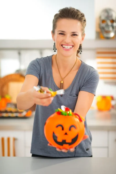 Woman holding halloween bucket and giving trick or treat candy — Stock Photo, Image