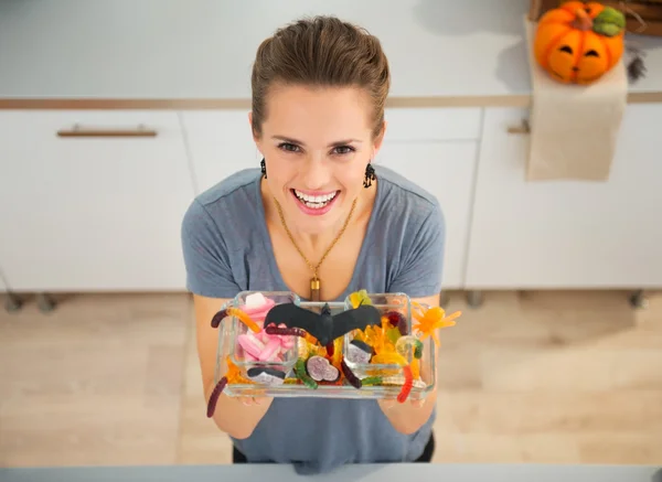 Woman showing dish with trick or treat candy for halloween party — ストック写真