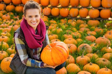 Oturma ve büyük kabak tutan gülümseyen kadın portresi