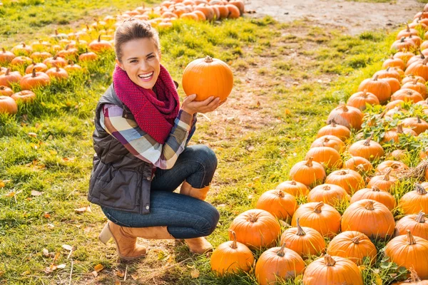 Retrato de una mujer sonriente eligiendo calabaza en la granja — Foto de Stock