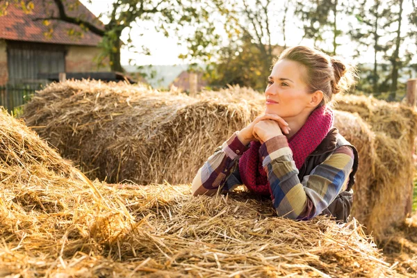 Портрет молодой женщины, стоящей рядом со стопкой сена на ферме — стоковое фото