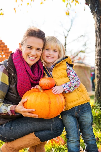 Portrait of woman and child holding pumpkins in autumn outdoors — Stock Photo, Image