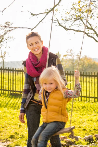 Portret van lachende vrouw en swingende kind in het najaar van buiten — Stockfoto