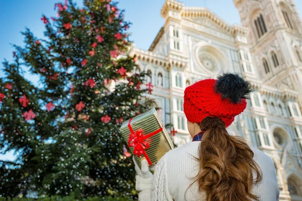 Seen from behind, woman holding Christmas gift box in Florence