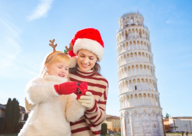 Mother in Christmas hat and daughter checking photos. Pisa