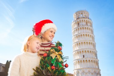 Woman and baby girl holding Christmas tree. Pisa, Italy
