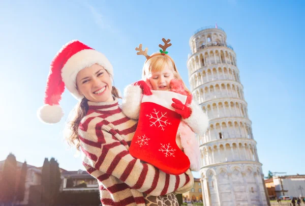 Mother with daughter looking into Christmas sock for gift, Pisa