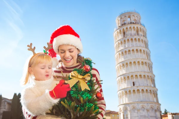 Happy mother and daughter holding Christmas tree. Pisa, Italy — Zdjęcie stockowe