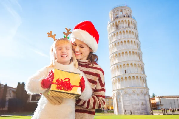 Woman in Christmas hat and baby girl holding gift box. Pisa — Zdjęcie stockowe