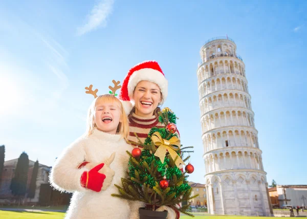 Happy woman and baby girl holding Christmas tree. Pisa, Italy — Zdjęcie stockowe