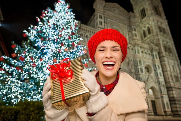 Женщина показывает подарочную коробку рядом с елкой во Флоренции, Италия — стоковое фото