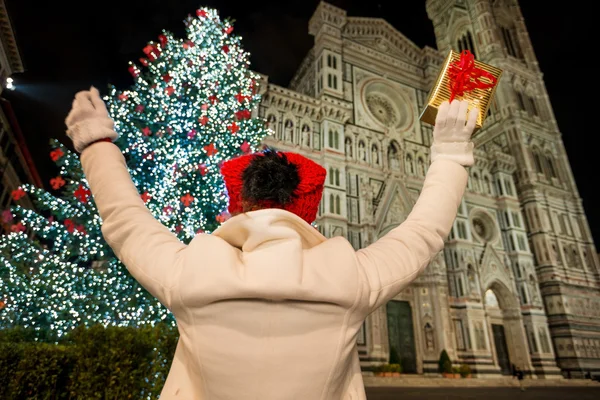 Woman with gift box rejoicing near Christmas tree in Florence — Stockfoto