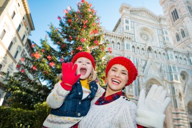 Mother and daughter handwaving near Christmas tree in Florence