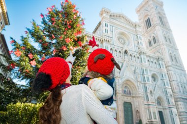 Seen from behind, daughter and mother pointing on Christmas tree