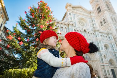 Mother and daughter hugging near Christmas tree in Florence