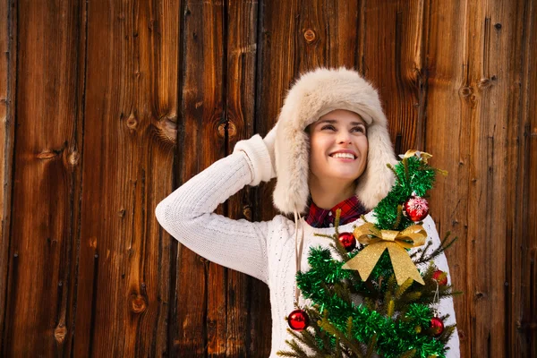 Frau mit Weihnachtsbaum nahe rustikaler Mauer schaut auf Kopierplatz — Stockfoto