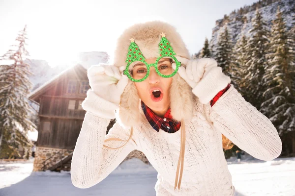 Neşeli bir yılbaşı kadında bir dağ evinin önünde gözlük — Stok fotoğraf