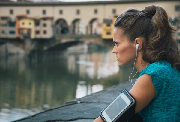 Young fitness female with mp3 player staying close to Arno river — Stockfoto