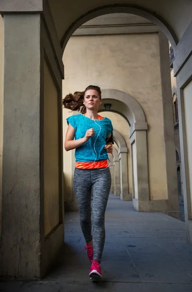 Fitness female with earphones is jogging outdoors — Stock fotografie