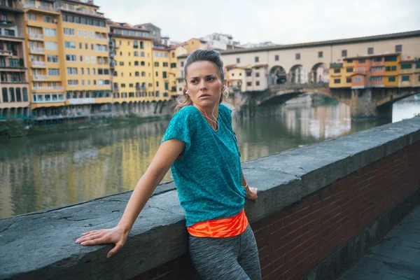 Mujer atlética joven se queda al lado del río Arno — Foto de Stock