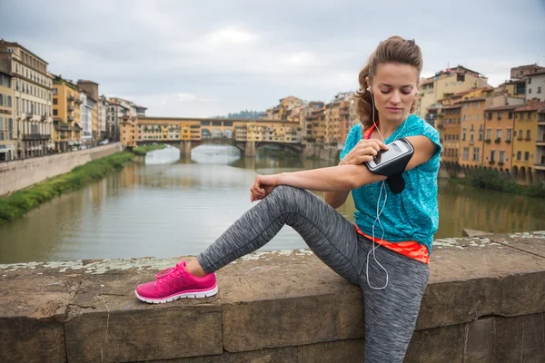 Sporty young woman sitting and listening mp3 player — ストック写真