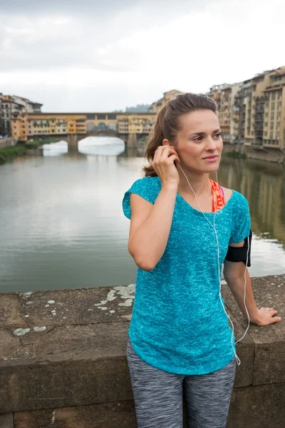 Relaxed fitness woman listening mp3 in front of Ponte Vecchio — Stockfoto