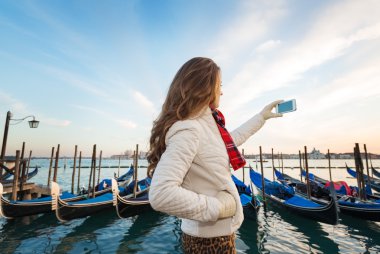 Woman traveler taking photos on embankment in Venice, Italy