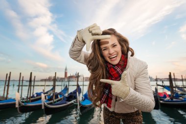Woman traveler framing with hands on embankment in Venice, Italy