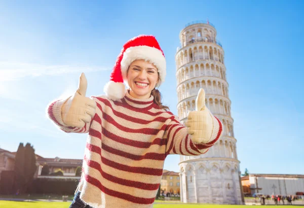 Mujer en Santa sombrero mostrando los pulgares hacia arriba cerca de inclinación Tour de Pisa — Foto de Stock