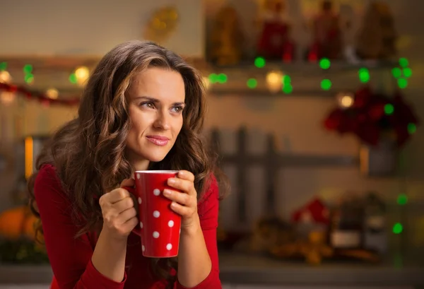 Donna che ha una tazza di cioccolata calda in cucina decorata di Natale — Foto Stock