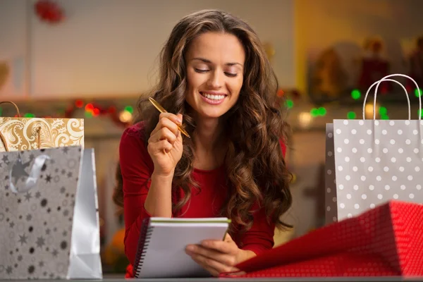 Mujer entre bolsas de compras lista de verificación en la cocina de Navidad — Foto de Stock