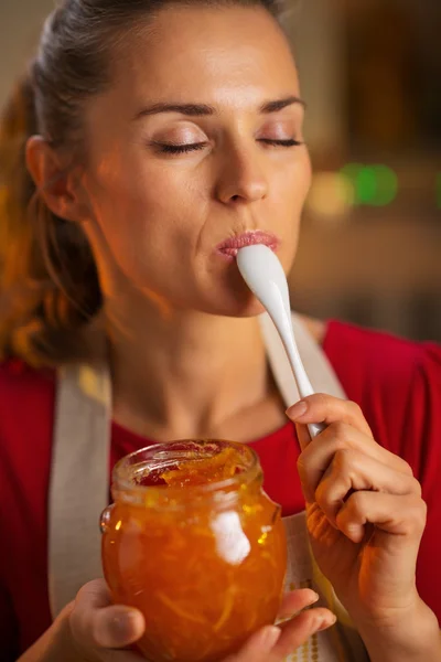 Joven ama de casa degustando una cucharada de mermelada de naranja casera —  Fotos de Stock